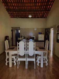 een eetkamer met een tafel en witte stoelen bij Recanto Girassol in Aquiraz