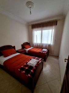 2 Betten in einem kleinen Zimmer mit Fenster in der Unterkunft Tangier Central Comforts: Your Moroccan Home with Cultural Proximity in Tangier