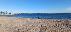 a woman sitting on a beach next to the water at ciel étoilé in Vallauris