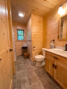 a log cabin bathroom with a toilet and a sink at Blissful Bear in Old Forge