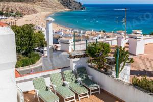 a group of chairs sitting on a balcony overlooking a beach at Maio Apartment in Luz
