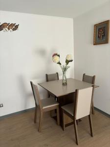 a dining room table and chairs with a vase of flowers at Acogedor departamento arica in Arica