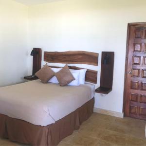 een slaapkamer met een bed met een houten hoofdeinde en een deur bij Casa del Golfo El Salvador in Conchagua