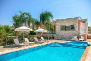 una piscina con sedie e ombrelloni accanto a una casa di Villa Harmonia - 4 Bedroom Luxury Beach Front Villa with Private Pool a Polis Chrysochous
