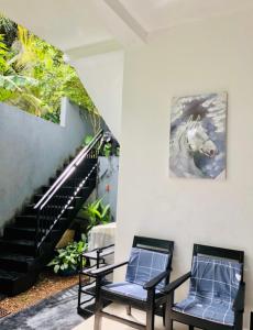 two chairs sitting next to a staircase with a painting of a horse at Nasareth Villa Unawatuna in Galle