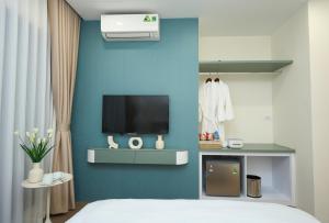 a bedroom with a bed and a tv on a blue wall at EDEN RESIDENCE in Hanoi