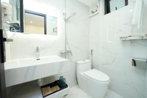 La salle de bains blanche est pourvue de toilettes et d'un lavabo. dans l'établissement EDEN RESIDENCE, à Hanoï