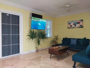 ein Wohnzimmer mit einem blauen Sofa und einem TV in der Unterkunft Private Guest House 2 bedrooms & 2 baths near Grace Bay Beach & Long Bay Beach. in Providenciales