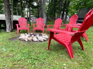trzy czerwone krzesła siedzące obok ogniska w obiekcie Ryder's Lodge w mieście Old Forge