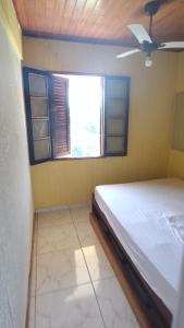 1 dormitorio con cama y ventana en Chalé Mirante do Félix (Amarelo) en Ubatuba