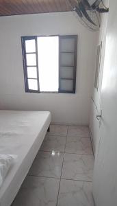 Habitación blanca con cama y ventana en Chalé Mirante do Félix (Amarelo) en Ubatuba