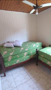 2 zielone łóżka w pokoju z sufitem w obiekcie Chalé Mirante do Félix (Amarelo) w mieście Ubatuba