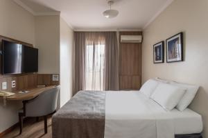 阿雷格里港的住宿－阿雷格里港千禧藍樹酒店，配有一张床和一张书桌的酒店客房