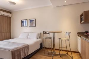 1 dormitorio con 1 cama, mesa y sillas en Blue Tree Towers Millenium Porto Alegre, en Porto Alegre