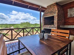 una mesa de madera en una terraza con chimenea en Marloth Kruger View, en Marloth Park