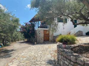 una casa con un vialetto in pietra e un muro in pietra di Haus mit Pool im Olivenhain a Koroni