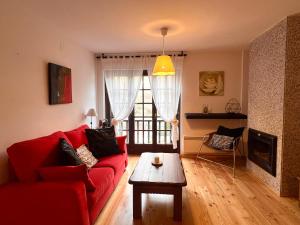 Sala de estar con sofá rojo y mesa de centro en Apartament de La Coma, en Llavorsí