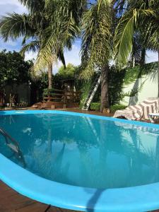 a blue swimming pool with palm trees in the background at Pousada Sossego in São Gabriel