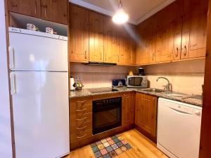 uma cozinha com um frigorífico branco e armários de madeira em Apartament de La Coma em Llavorsí