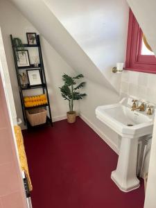 uma casa de banho com um lavatório e um piso vermelho em The Turret- the best view in Folkestone em Folkestone
