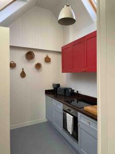 uma cozinha com armários vermelhos e um forno com placa de fogão em The Turret- the best view in Folkestone em Folkestone