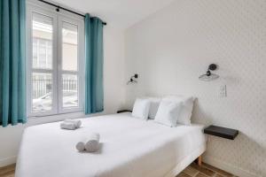 a bedroom with two white beds and a window at Très bel appartement pour 4 aux portes de Paris in Aubervilliers