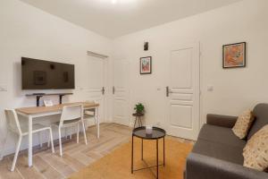 a living room with a couch and a table and a tv at Très bel appartement pour 4 aux portes de Paris in Aubervilliers