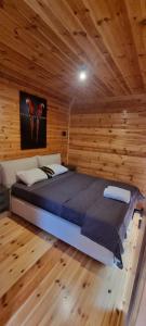 a large bed in a room with a wooden wall at Pirates Nest Cottages in Ulcinj