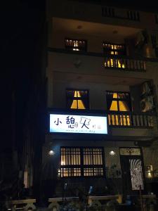 un bâtiment avec un panneau devant lui la nuit dans l'établissement 小憩人輕旅, à Jinning