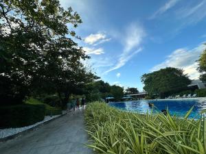 people walking along a path next to a swimming pool at 14DC Tambuli Seaside Living in Lapu Lapu City