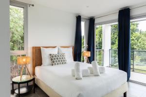 a bedroom with a large white bed with windows at Le Domaine de l'Anse Mitan in Les Trois-Îlets