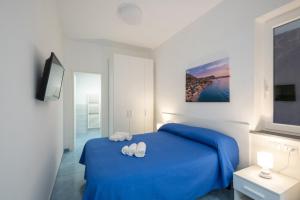 una camera con un letto blu e due asciugamani bianchi di B&B La Vigna Rooms - Ischia Ponte a Ischia
