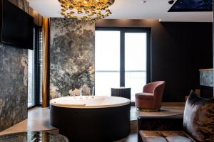 a large bathroom with a tub and a chair at Art Suites Luxury Hotel in Kraków