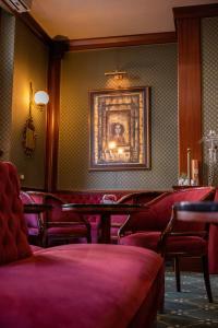 a waiting room with red chairs and a painting on the wall at Hotel Mecenate Palace in Rome