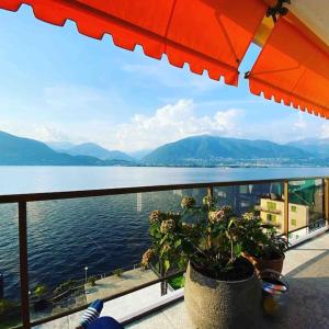 a view of the water from a balcony with an umbrella at Exclusive Lakeside Apartment with Amazing View in Gambarogno