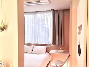Habitación pequeña con cama y ventana en 东京中心上野公园时尚设计师房间Ycoc 上野公园3分钟 车站1分钟 超级繁华 免费wifi 戴森吹风, en Tokio