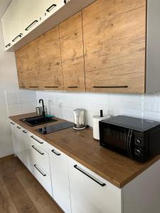 La cuisine est équipée de placards blancs et d'un four micro-ondes noir. dans l'établissement Apartament w chmurach, à Toruń