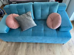 - un canapé bleu avec 2 oreillers roses dans l'établissement Apartament w chmurach, à Toruń