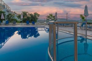 einen Pool in einem Resort mit Sonnenuntergang in der Unterkunft Nefeli Beach - living by the sea in Argassi