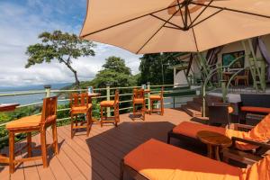 un patio con mesas, sillas y una sombrilla en Issimo Suites (Adults Only), en Manuel Antonio