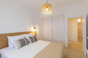 Un dormitorio con una gran cama blanca y una lámpara en Faro Guest Apartments, en Faro