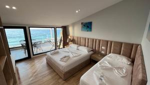 a bedroom with two beds and a view of the ocean at Hotel Tramonto Vlore in Vlorë