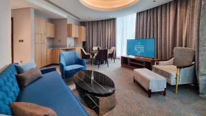 a living room with a blue couch and a television at Millennium Place Doha in Doha