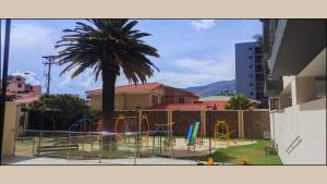 a playground in front of a building with a palm tree at Departamento Vistas Ambar - 1 Dormitorio in Cochabamba