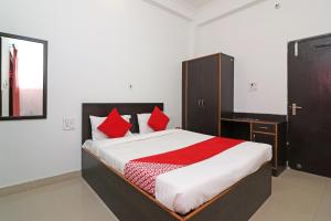 una camera da letto con un grande letto con cuscini rossi di OYO Flagship 24199 Hotel Ojus Tower a Rudrapur