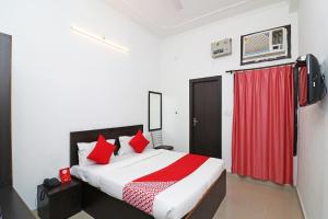 a bedroom with a bed with red pillows and a red curtain at OYO Flagship 24199 Hotel Mid Town Ojus Tower in Rudrapur