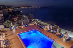 a swimming pool with chairs and the ocean at night at Nefeli Beach - living by the sea in Argasi