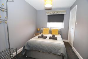 um quarto com uma cama com almofadas amarelas e uma janela em Harbour View City Centre Apartment em Belfast