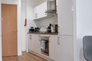 a kitchen with white cabinets and a stove top oven at Luxury Central Apartment - Smart TV - Fast WIFI - Near Utilitia Arena in Birmingham
