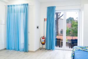 een kamer met blauwe gordijnen en een brandblusser bij Summer Colors rooms & apartments in Meta